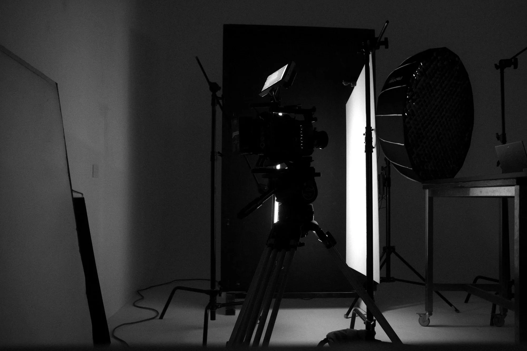 A cinema camera on a tripod in a lit production studio
